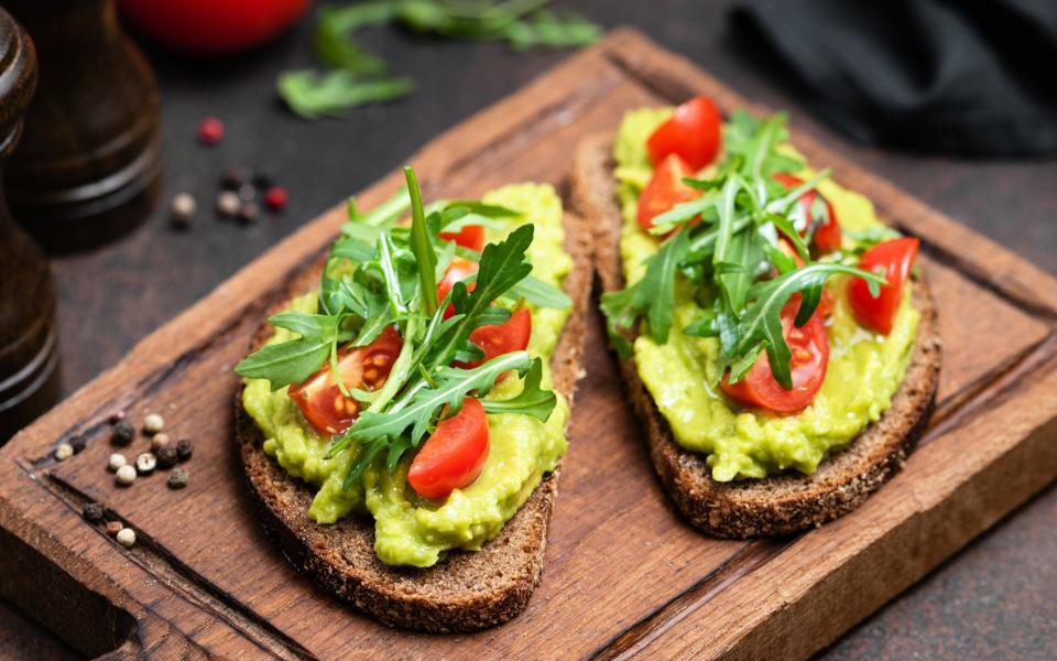 wholegrain toast with sliced avocado and tomato for breakfast - Getty