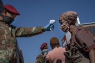 FILE - In this file photo taken Wednesday May 20, 2020, South African National Defense Forces check the temperature of people near the Pan Africa taxi rank in Johannesburg's Alexandra township. South Africa is struggling to balance its fight against the coronavirus with its dire need to resume economic activity. The country with the Africa’s most developed economy also has its highest number of infections — more than 19,000. (AP Photo/Jerome Delay, File)