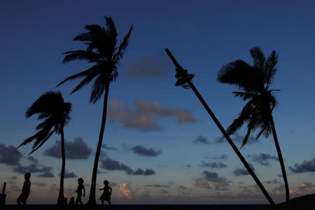 People are seen in silhouette walking on a beach affected by Hurricane Maria in San Juan, Puerto Rico, October 13, 2017. REUTERS/Shannon Stapleton