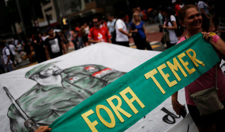 Women hold a banner that reads "Out Temer", referring to Brazil's President Michel Temer, in front of a painting of Cuba's former President Fidel Castro during a protest against a constitutional amendment, known as PEC 55, that limits public spending, in Sao Paulo, Brazil, November 27, 2016. REUTERS/Nacho Doce