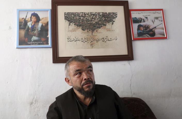 Rajab Ali Urzgani Mangol speaks during an interview to The Associated Press in Kabul, Afghanistan, Tuesday, June 1, 2021. On the wall are photos of 14-year-old Mangol as a Hazara fighter during the Afghan civili war. After the collapse of the Taliban 20 years ago, Afghanistan's ethnic Hazaras began to flourish and soon advanced in various fields, including education and sports, and moved up the ladder of success. They now fear those gains will be lost to chaos and war after the final withdrawal of American and NATO troops from Afghanistan this summer. (AP Photo/Rahmat Gul)