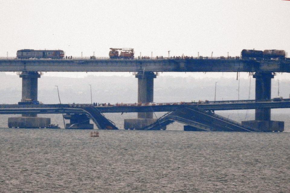 Workers restore the railway tracks on the Kerch bridge that links Crimea to Russia, near Kerch, on October 9, 2022, a day after it was damaged by a blast.