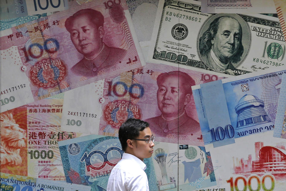 FILE - In this June 10, 2019, file photo, a man walks past a money exchange shop decorated with different banknotes at Central, a business district of Hong Kong. China's yuan fell Friday, Aug. 2, 2019, to its lowest level of the year against the dollar following U.S. President Donald Trump's threat of new tariffs on Chinese goods, coming close to breaking the politically sensitive level of seven to the U.S. currency. (AP Photo/Kin Cheung, File)