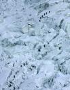 FILE - In this May 18, 2003 file photo, mountaineers pass through the treacherous Khumbu Icefall on their way to Mount Everest near Everest Base camp, Nepal. The Khumbu Icefall is a river of ice, a kilometer or so of constantly shifting glacier punctuated by deep crevasses and overhanging immensities of ice that can be as large as 10-story buildings and can move six feet in just one day. Crossing it can take 12 hours. On Friday, April 18, 2014, a piece of glacier sheared away from the mountain, setting off an avalanche of ice that killed 16 Sherpa guides as they ferried clients’ equipment up the mountain. (AP Photo/Gurinder Osan, File)