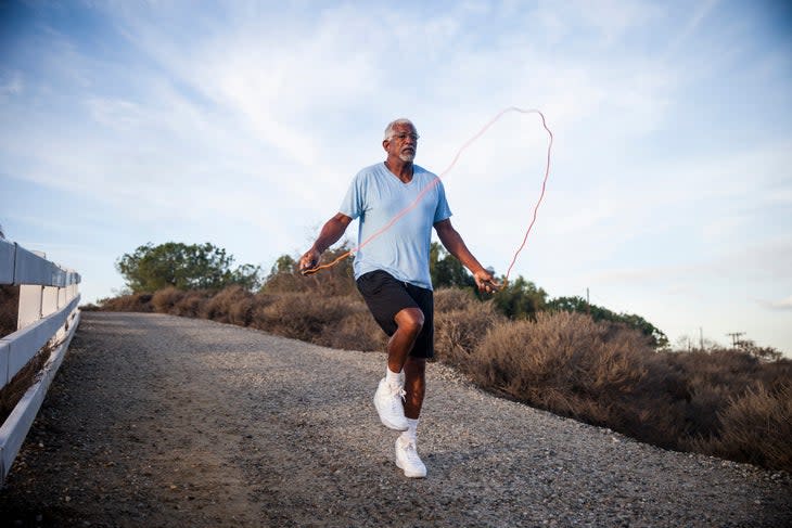 senior man jumps rope outside on gravel trail