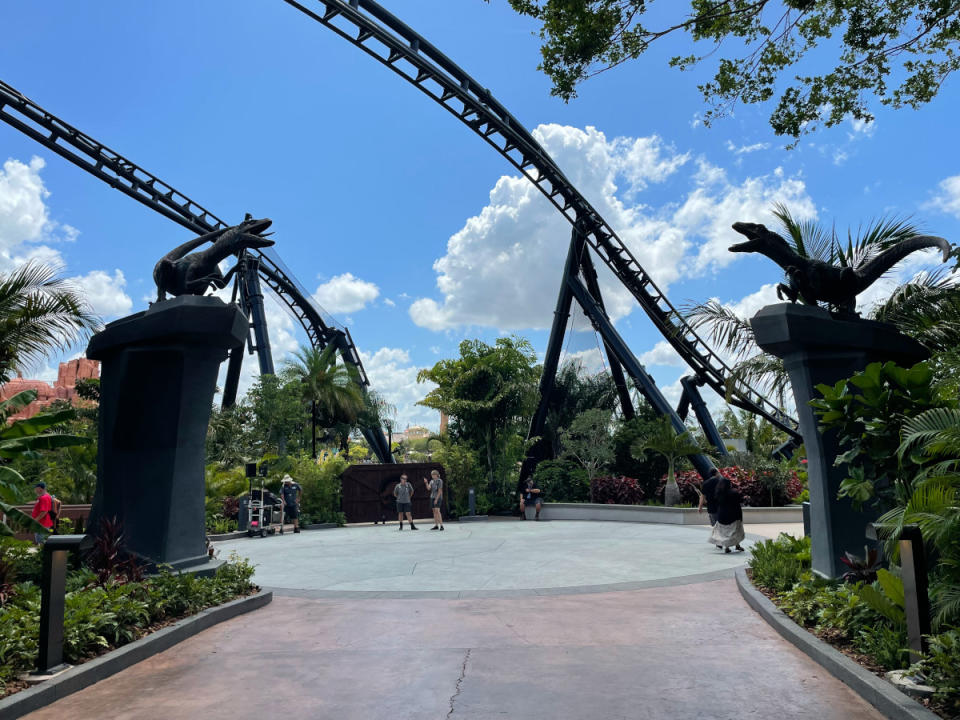 Two raptor statues on pedestals in front of the VelociCoaster