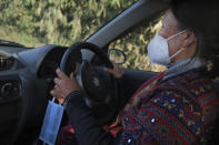 An extra face mask hangs by the steering wheel of nurse Shimray Wungreichon, 43, as she drives home from a day at work at the District Hospital in Ukhrul, in the northeastern Indian state of Manipur, Friday, Jan. 15, 2021. For the first three months, she couldn’t hug her three children, fearing she could potentially pass the virus to them. Her aged parents were to spend all of 2020 living with her, but it was too risky to live with a nurse so they moved back to their distant home village. And her anxiety spiked with every coronavirus test she conducted. (AP Photo/Yirmiyan Arthur)