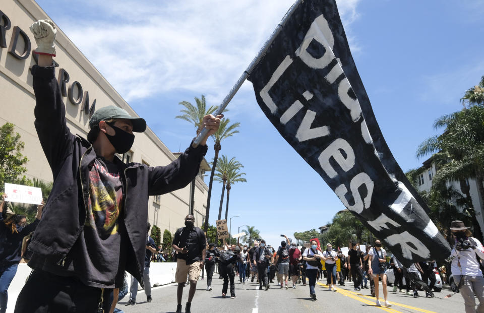 A man holds a flag during a protest over the death of George Floyd in Los Angeles, Saturday, May 30, 2020. Protests across the country have escalated over the death of George Floyd who died after being restrained by Minneapolis police officers on Memorial Day, May 25.(AP Photo/Ringo H.W. Chiu)