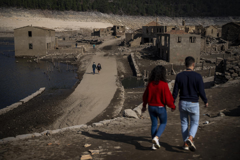 Visitors walk at the old village of Aceredo emerged due to drought at the Lindoso reservoir, in northwestern Spain, Friday, Feb. 11, 2022. Large sections of Spain are experiencing extreme or prolonged drought, with rainfall this winter at only one-third of the average in recent years. The situation is similar in neighboring Portugal, where 45% of the country is now enduring “severe” or “extreme” drought. (AP Photo/Emilio Morenatti)