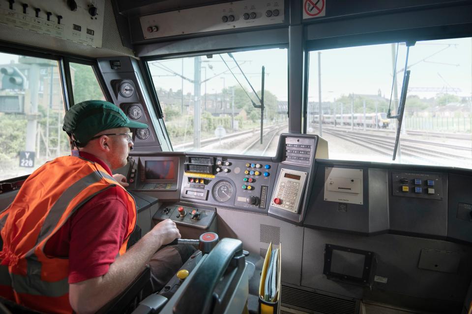 Train driver in stationary locomotive on train tracks.