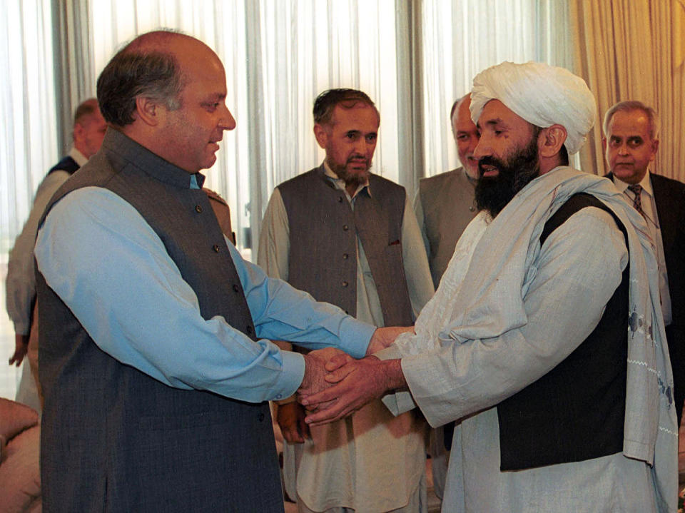 FILE - In this Aug. 25, 1999 file photo, Mullah Hasan Akhund, right, then Afghanistan's Foreign Minister is received by then Pakistan Prime Minister Nawaz Sharif, in Islamabad. The Taliban on Tuesday, Sept. 7, 2021, announced a caretaker Cabinet that paid homage to the old guard of the group, giving top posts to Taliban personalities who dominated the 20-year battle against the U.S.-led coalition and its Afghan government allies. Akhund who was named Interim Afghan Prime Minister on Tuesday, headed the Taliban government in Kabul during the last years of its rule. (AP Photo/B.K. Bangash, File)
