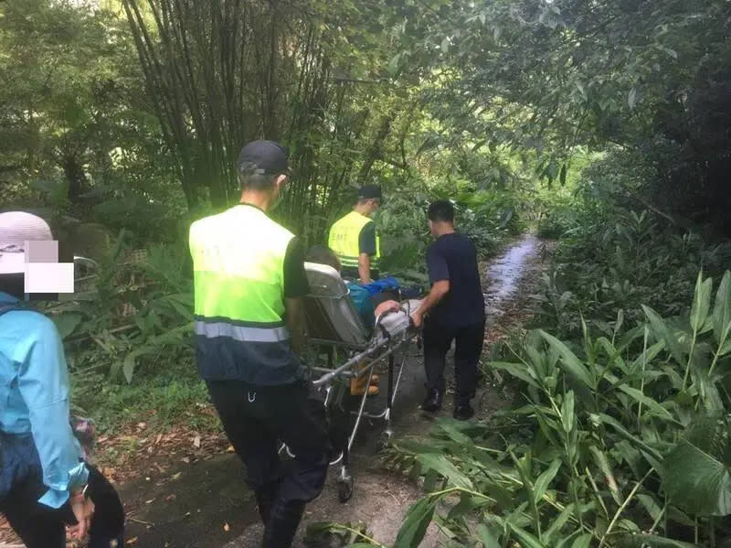 ▲今（9）日有7名山友結伴登新北市萬里區富士坪古道，其中一名56歲的山友禁不起炎熱，中暑導致雙腳無力，新北市消防局9名消防員獲報上山救援，輪流攙扶下山，送內湖三軍總醫院。（圖／翻攝畫面）