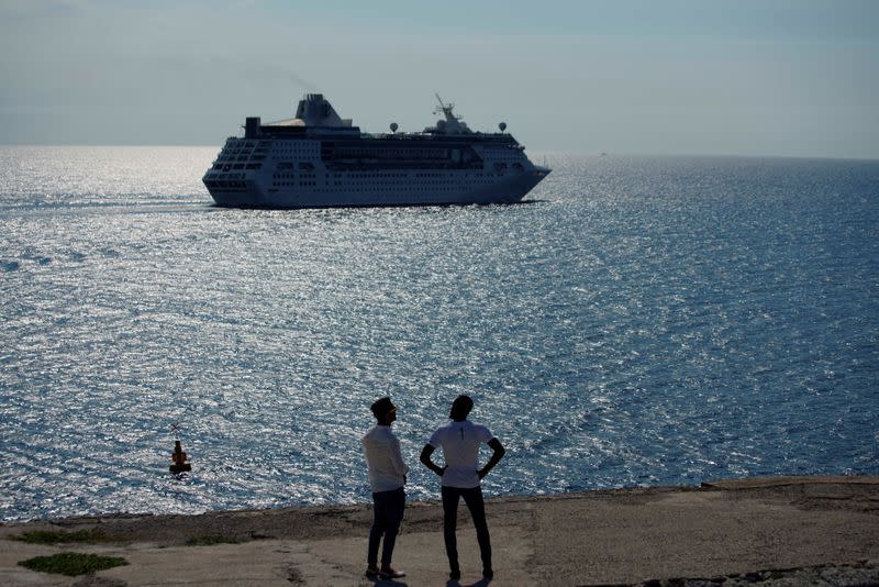FILE PHOTO: Men watch the cruise ship MS Empress of the Seas, operated by Royal Caribbean International, as it leaves the bay of Havana