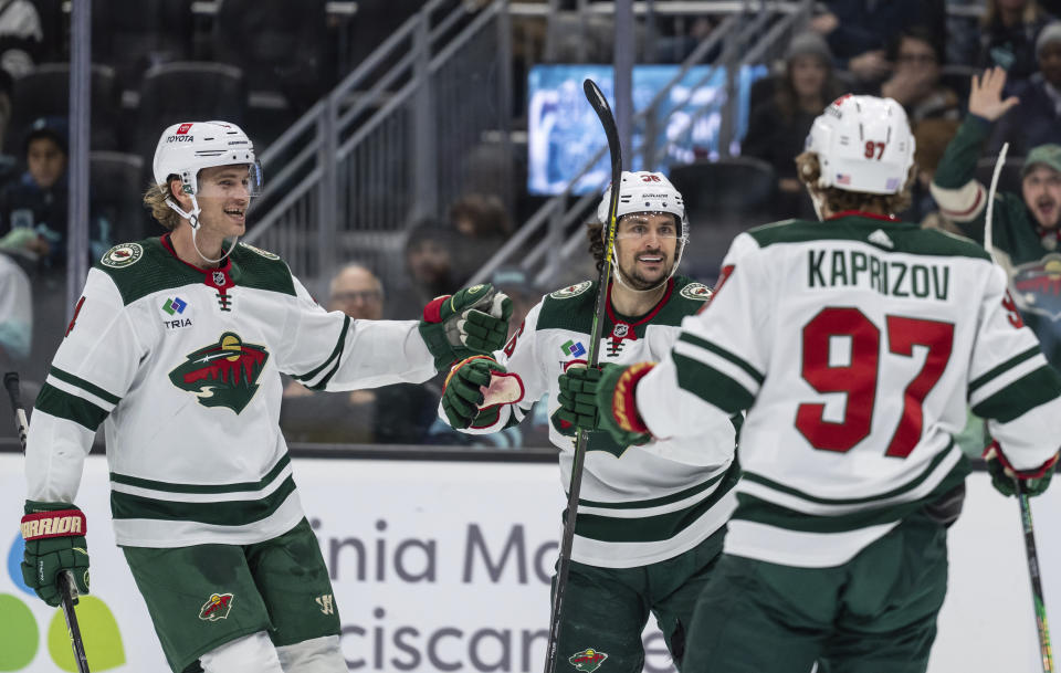 Minnesota Wild forward Mats Zuccarello, center, is congratulated by defenseman Jon Merrill, left, and forward Kirill Kaprizov for his goal during the first period of the team's NHL hockey game against the Seattle Kraken, Friday, Nov. 11, 2022, in Seattle. (AP Photo/Stephen Brashear)