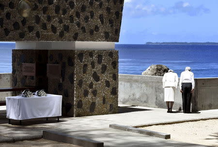 Japan's Emperor Akihito (R) and Empress Michiko bow towards Angaur Island after they offered flowers to the cenotaph (L) for the war dead in the western Pacific area, on Palau's Peleliu Island, in this photo released by Kyodo April 9, 2015. Mandatory Credit REUTERS/Kyodo