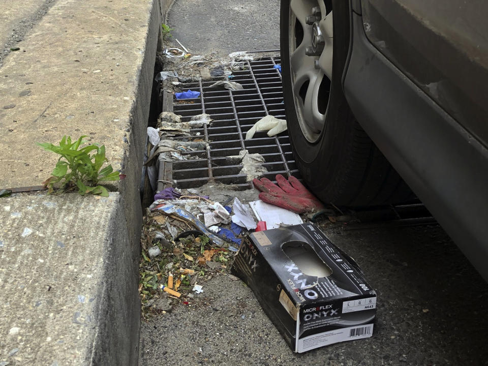 This Friday, May 22, 2020 photo shows a discarded glove on a storm drain in Philadelphia. Between mid-March, when the city’s stay-at-home order was issued, and the end of April, most of the 19 sewer and storm water pumping stations in Philadelphia had experienced clogs from face masks, gloves and wipes residents had pitched into the potty, Philadelphia Mayor Jim Kenney said. (AP Photo/Jonathan Poet)