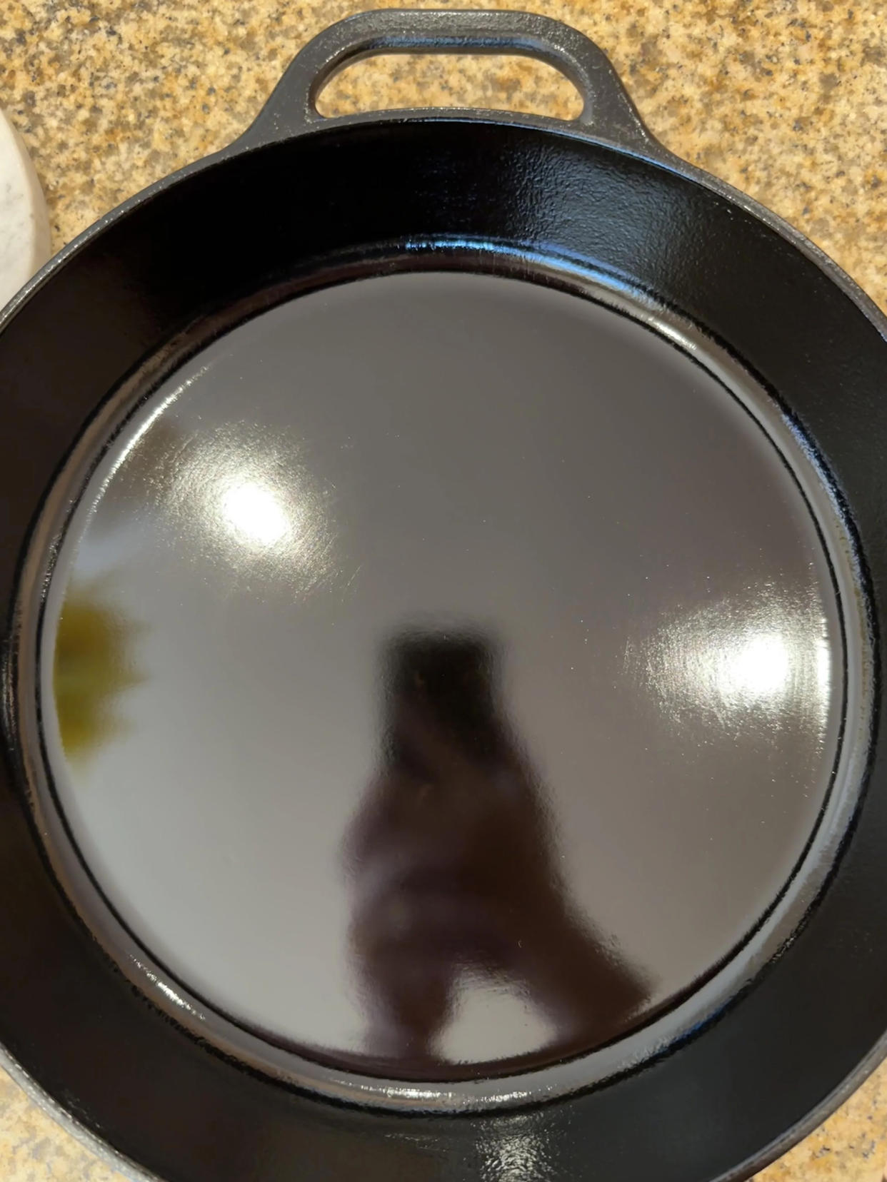 Dewey's cast-iron skillet with 80 coats of seasoning and his phone in the reflection. (Courtesy u/fatmummy222 via Reddit)
