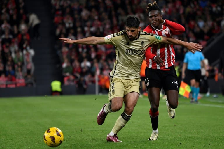 El defensor uruguayo del Granada Bruno Méndez (izquierda) pugna por el balón con el extremo del Athletic Club Nico Williams durante el partido de Liga entre amgos equipos en San Mamés, en Bilbao, el 19 de abril de 2024 (ANDER GILLENEA)