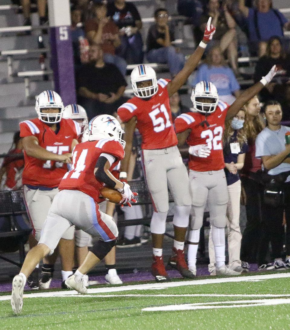 Teammates on the sideline cheer on as Alliance's Carter Bugara (14) returns an interception against Salem during a game in September 2021.