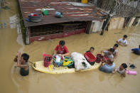 Residents give away onions and other foods along a flooded road due to Typhoon Noru in San Miguel town, Bulacan province, Philippines, Monday, Sept. 26, 2022. Typhoon Noru blew out of the northern Philippines on Monday, leaving some people dead, causing floods and power outages and forcing officials to suspend classes and government work in the capital and outlying provinces. (AP Photo/Aaron Favila)