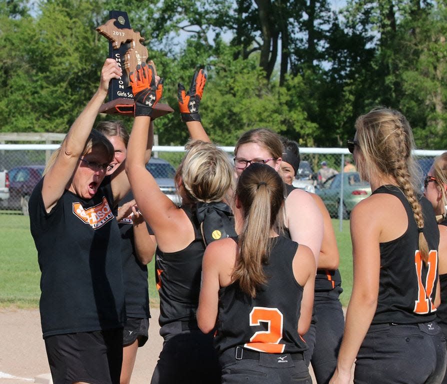 Hudson softball coach Amy Hill lifts up the district championship trophy and hands it to her players after winning it in 2017.