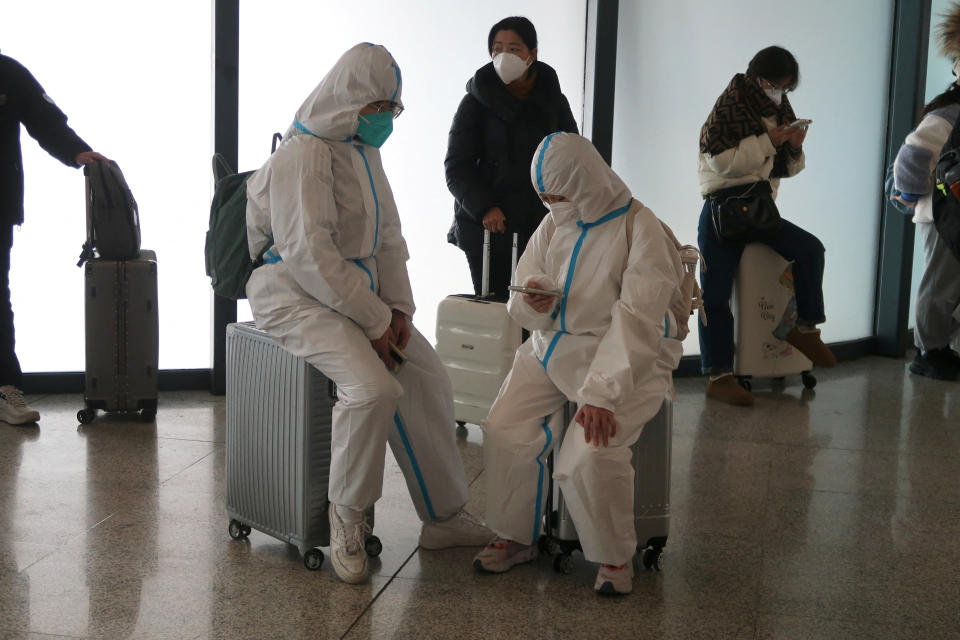 People in protective suits wait in a bus stop shelter of a train station after the government eased control of the coronavirus disease (COVID-19) in Wuhan, China's Hubei province, 11 December 2022.  REUTERS/Martin Pollard