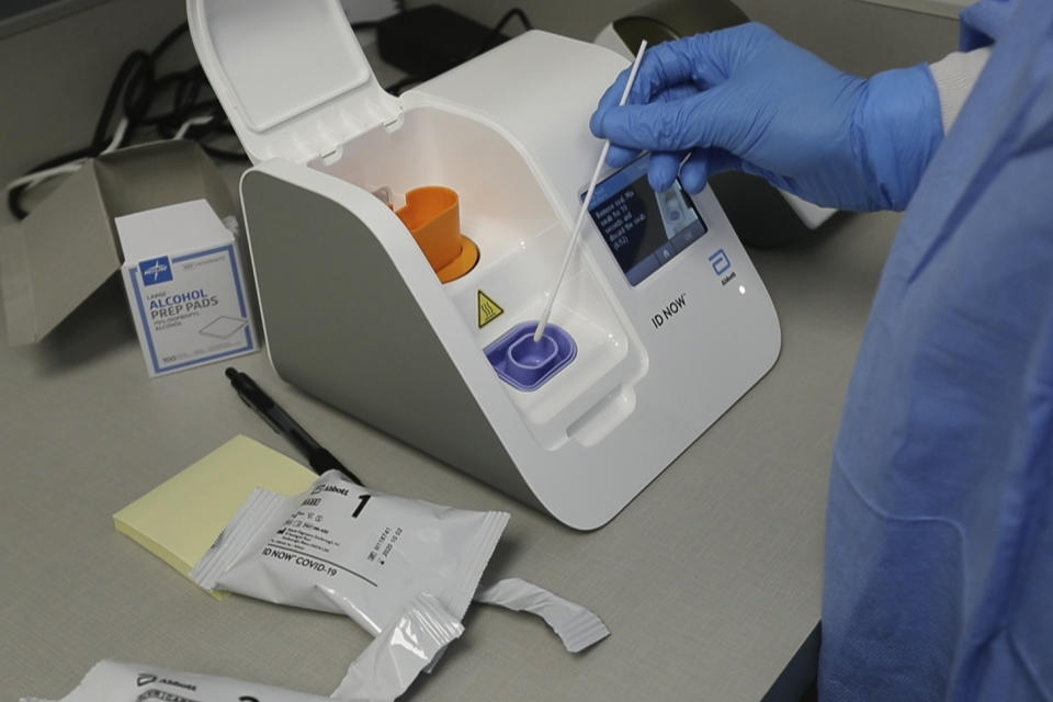 En esta imagen tomada de un video, 10 de abril de 2020, un técnico de laboratorio coloca una muestra en el aparato para pruebas de Abbott Laboratories en el Centro de Salud de Detroit. Durante meses, el presidente Donald Trump y sus funcionarios han emitido una niebla de promesas para tranquilizar a un país atrapado en por la pandemia de coronavirus, pero no han cumplido las cruciales. (AP Foto/Carlos Osorio)