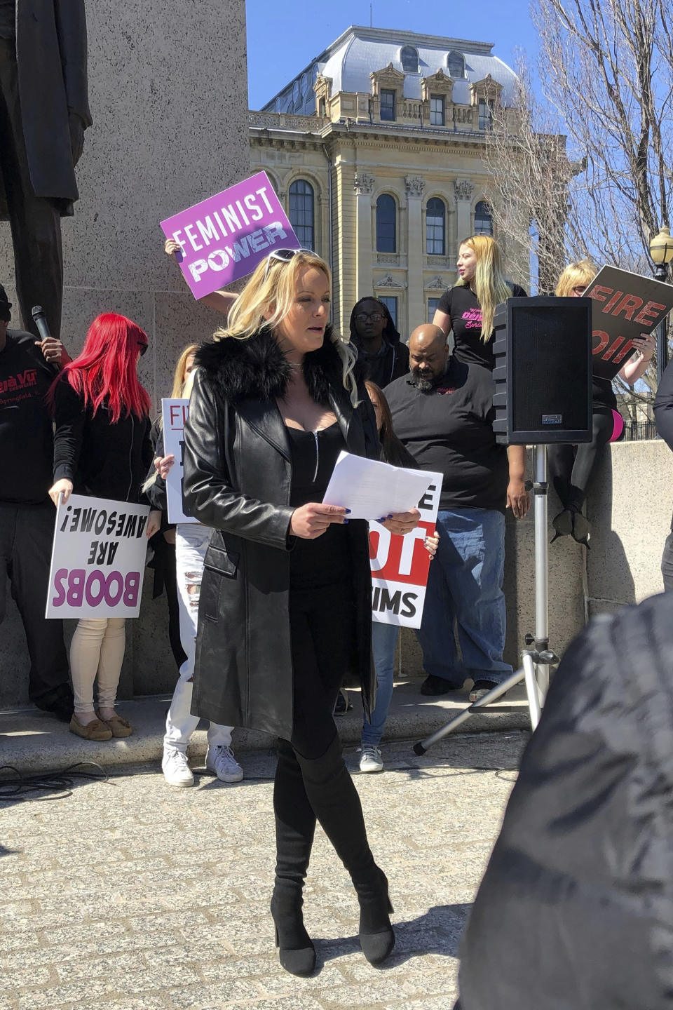 Adult film star Stormy Daniels reads a statement, protesting the Illinois surcharge on live adult entertainment centers, beneath the statue of Abraham Lincoln at the state Capitol, Friday, March 22, 2019 in Springfield, Ill. The actress famous for her alleged affair with Donald Trump before he became president read a two-minute statement before she was whisked off to a local strip club to sign copies of her book. Daniels, whose real name is Stephanie Clifford, says the tax unfairly ties nude dancing to violence against women and that it "takes money out of the g-strings of hardworking young dancers." (AP Photo/John O'Connor)