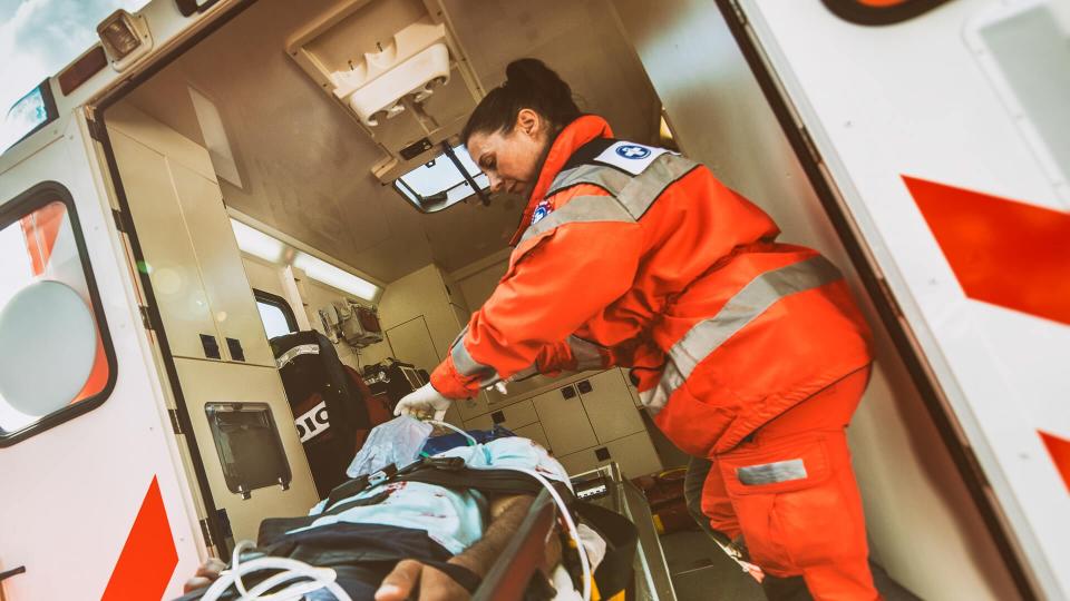 Paramedic team pushing stretcher with injured person towards ambulance.