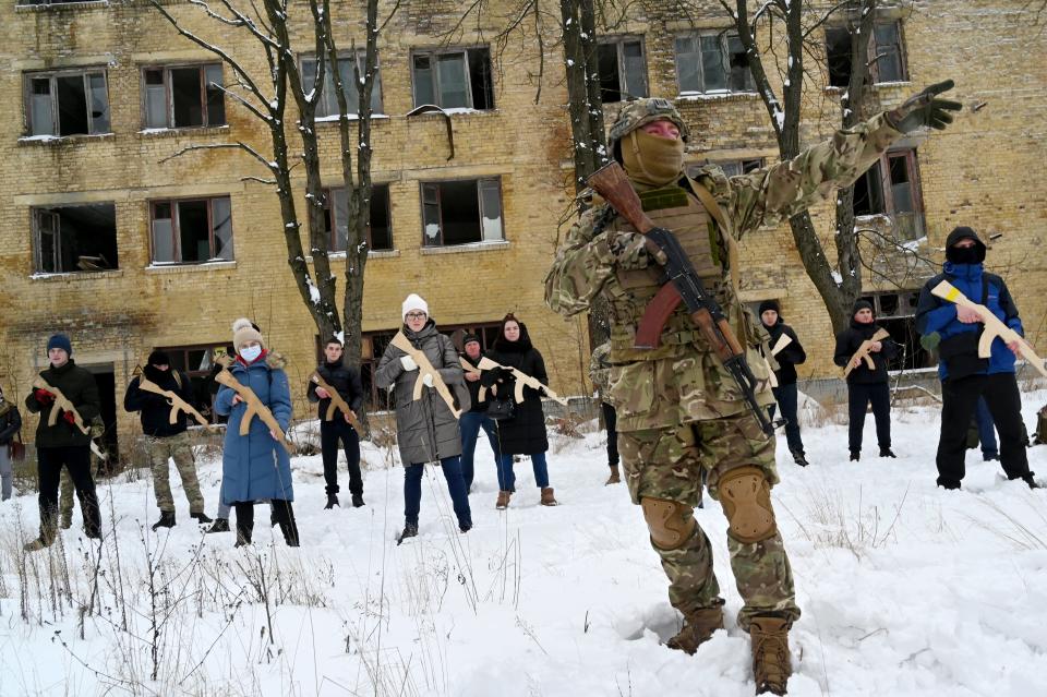 A military instructor teaches civilians holding wooden replicas of Kalashnikov rifles, during a training session at an abandoned factory in the Ukrainian capital of Kyiv on January 30, 2022. (Sergei Supinsky/AFP via Getty Images)