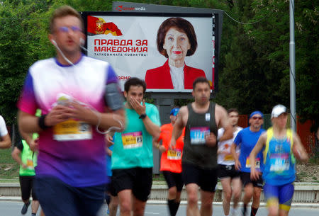 Runners run during the Skopje Marathon next to an election campaign poster of the opposition party VMRO-DPMNE presidential candidate Gordana Siljanovska-Davkova before the presidential election on May 5, in Skopje, North Macedonia May 4, 2019. REUTERS/Ognen Teofilovski