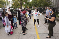 Teachers, right, ask parents and students if they have completed health surveys before the students enter PS 179 elementary school in the Kensington neighborhood, Tuesday, Sept. 29, 2020 in the Brooklyn borough of New York. Hundreds of thousands of elementary school students are heading back to classrooms Tuesday as New York City enters a high-stakes phase of resuming in-person learning during the coronavirus pandemic. (AP Photo/Mark Lennihan)