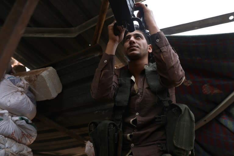 A Syrian rebel fighter from the National Liberation Front aims his machinegun on the front line with regime forces in the southeast of Idlib province on October 9, 2018