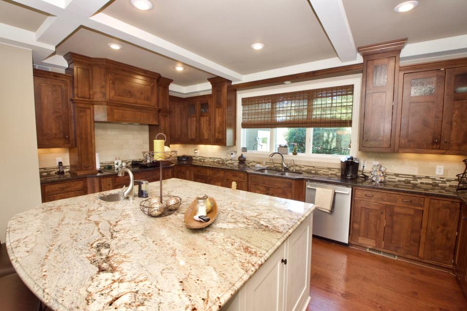 The kitchen has coffered ceilings and a large island featuring a vegetable sink and fridge drawer. The island is large enough for breakfast seating.