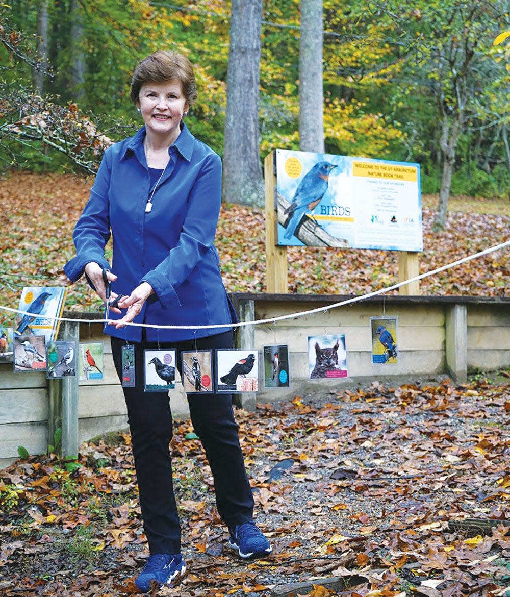 Author Shirley Raines cuts the ribbon for the UT Arboretum’s Nature Book Trail, which now has signs based on her book.