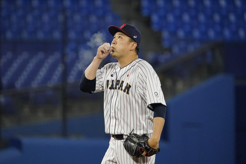 Japan's Masahiro Tanaka blows chalk off of his hand during a baseball game against the United States at the 2020 Summer Olympics, Monday, Aug. 2, 2021, in Yokohama, Japan. (AP Photo/Sue Ogrocki)