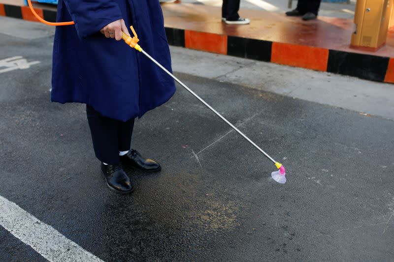 A staff member sanitize the floor at an entrance of a residential complex, as the country is hit by an outbreak of the new coronavirus in Beijing