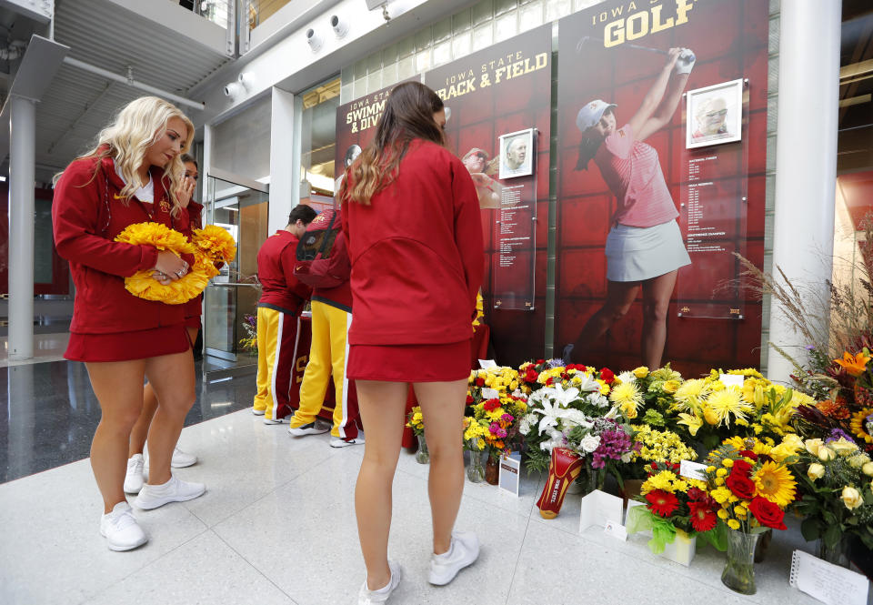 Iowa State cheerleaders look at a memorial to honor slain student Celia Barquin Arozamena, seen in photo at right, before an NCAA college football game between Iowa State and Akron, Saturday, Sept. 22, 2018, in Ames, Iowa. Barquin, who was the 2018 Big 12 women's golf champion and Iowa State Female Athlete of the Year, was found Monday morning in a pond at a golf course near the Iowa State campus. (AP Photo/Charlie Neibergall)