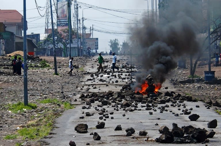 People walk past a burning barricade during a nationwide protest against long-serving President Joseph Kabila, in Goma on May 26, 2016