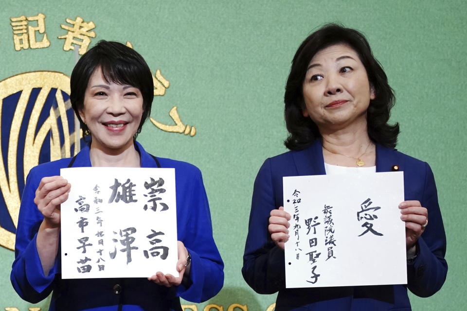 Sanae Takaichi, left, and Seiko Noda, right, both former internal affairs ministers and candidates for the presidential election of the ruling Liberal Democratic Party, show their motto on cards, during a debate session held by Japan National Press club Saturday, Sept. 18, 2021 in Tokyo. Takaichi and Noda are the first women in 13 years seeking the leadership of the ruling Liberal Democratic Party in an election Wednesday, Sept. 29. (AP Photo/Eugene Hoshiko, Pool)