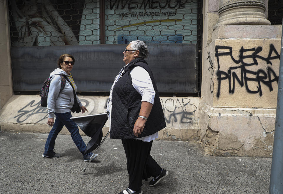 In this Nov. 4, 2019 photo, retired Magdalena Alvarez, 64, walks away after taking part in a protest against Chile's President Sebastian Pinera, in downtown Santiago, Chile. Álvarez, who works at a human rights organization and has a disability pension, said that the existing pension system needs to go “because in the end, the people who win are the ones who are managing the money.” (AP Photo/Esteban Felix)