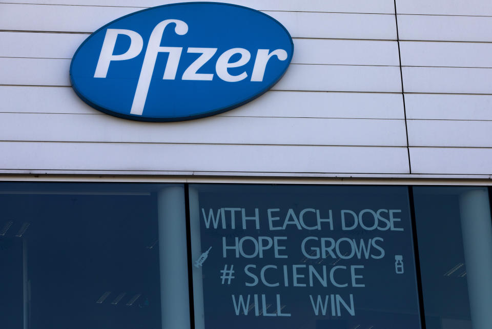 A sign is pasted into an upper window at Pfizer manufacturing center in Puurs, Belgium, Tuesday, Feb. 23, 2021. Two U.K. studies released Monday showed that COVID-19 vaccination programs are contributing to a sharp drop in hospitalizations, boosting hopes that the shots will work as well in the real world as they have in carefully controlled studies. (AP Photo/Virginia Mayo)