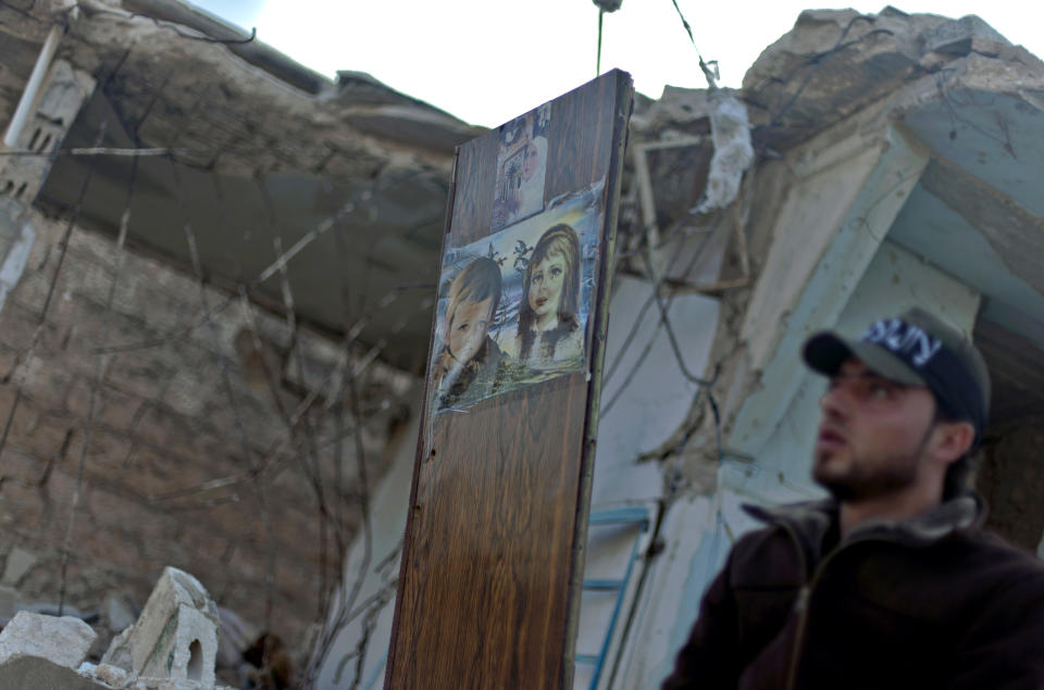 FILE - In this Friday, Nov. 16, 2012 file photo, A Free Syrian Army fighter stands next to a painting on a piece of wood left in a destroyed house in the town of Taftanaz, on the outskirts of Idlib, Syria. Syria’s uprising was not destined to be quick. Instead, the largely peaceful protest movement that spread across the nation slowly turned into an armed insurgency and eventually a full-blown civil war. More than 130,000 people have been killed, and more than 2 million more have fled the country. Nearly three years after the crisis began, Syria's government and opposition are set to meet in Geneva this week for the first direct talks aimed at ending the conflict. (AP Photo/Khalil Hamra, File)