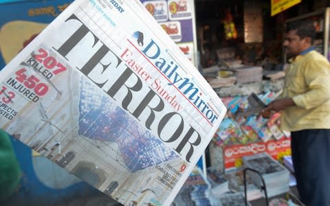 he front page of a Sri Lankan newspaper, showing coverage of the Easter Sunday blasts, hangs at a newsstand in Colombo  - Credit: AFP