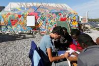 Migrants learn French with a volunteer in the "Jungle School" in southern area of the camp called the "Jungle" in Calais, France, September 25, 2016. REUTERS/Pascal Rossignol