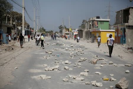 People walk along a road blocked by rocks in Croix-des-Bouquets, Haiti, July 8, 2018. REUTERS/Andres Martinez Casares