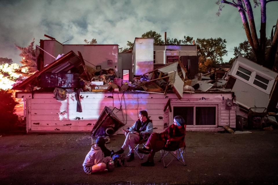 Bridget Casey sits in the driveway of her severely damaged home with her son Nate, 16, and daughter Marion, 14 (AP)