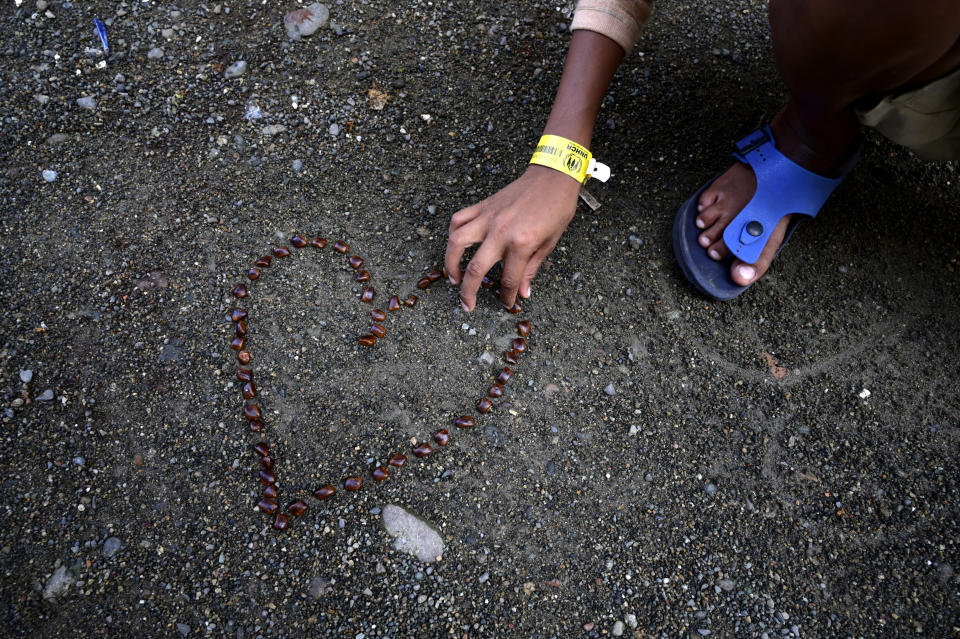 Umar Faruq, a 9-year-old ethnic Rohingya refugee who survived a boat capsize, arranges tamarind seeds in the shape of a heart at a temporary shelter in Meulaboh, Indonesia, on Wednesday, April 3, 2024. Umar was among 75 people rescued in March from atop the overturned hull of the boat, which capsized off Indonesia's coast. Dozens of other Rohingya refugees, including at least 28 children, died. (AP Photo/Reza Saifullah)
