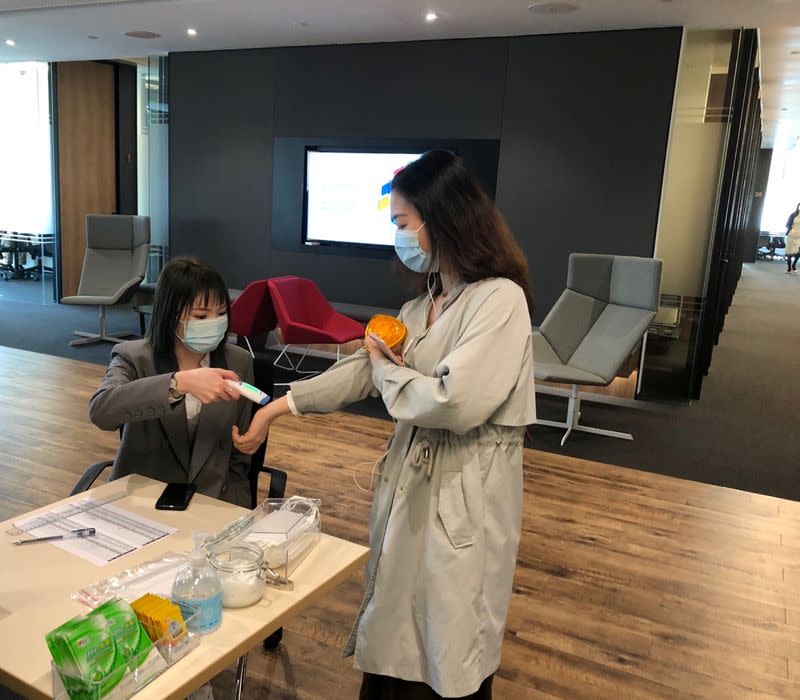 An employee has her temperature checked before entering PageGroup's office after reopening, as the coronavirus disease (COVID-19) continues, in Shanghai
