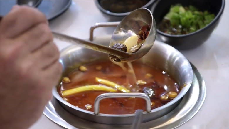 Andrew Zimmern ladling hot pot ingredients